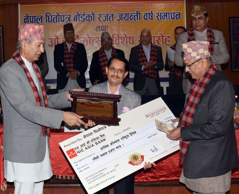 Editor-in-chief of New Business Age, Madan Lamsal (C), receives a cheque from Finance Minister Yuba Raj Khatiwada on behalf of New Business Age after being awarded with the 'Capital Market Journalism Award' on the occasion of the 26th anniversary of SEBON on Friday.