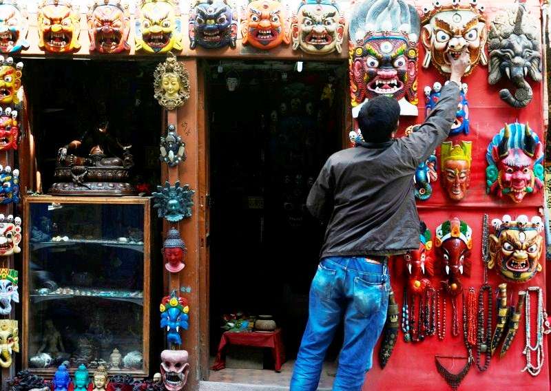 Owner of a curio shop at Lalitpur Durbar Square arranging masks at his shop on Wednesday. The shopkeepers say that foreigners are more interested in buying their products than the locals. Photo: Ravi Maharjan/NBA